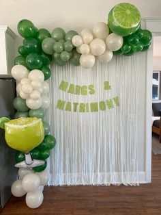 a balloon arch with limes and balloons on the wall for a margarita themed birthday party