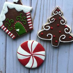 three decorated cookies sitting on top of a white wooden table next to a candy cane