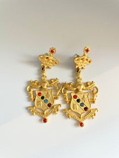 Vintage gold Etruscan style crown and shield/crest earrings with colorful rhinestone details. Great vintage condition. post style. signed JJ.  Please Note: All of these items are vintage. They have been pre-loved and are not in pristine condition. I try to take photos of any areas of concern. Please ask for more photos if you have any concerns about the condition of a piece. Returns will only be accepted if there is damage in shipping. Birmingham, Vintage Gold, More Photos, Jewelry Earrings Dangle, Etsy Earrings, Dangle Drop Earrings, Dangle Earrings, Jewelry Earrings, Crown