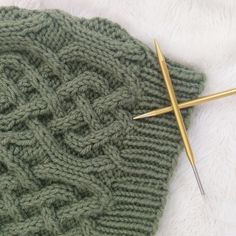 the knitting needles are next to the green knitted hat