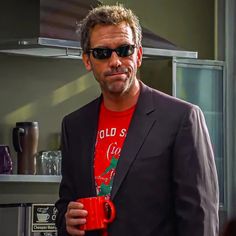 a man wearing sunglasses holding a red coffee mug