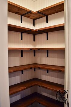 an empty walk in closet with wooden shelves and black brackets on the wall above it