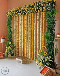 an arrangement of yellow flowers and greenery on the side of a wall in a room