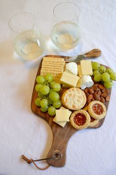 a wooden cutting board topped with grapes and crackers