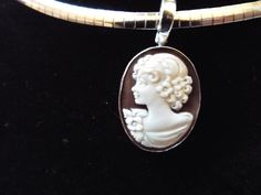 "This is a hand carved sardonyx cameo measuring 20 mm (0.79\") by 25 mm (0.98\") set in sterling silver. Bail is an enhancer of 5 mm in size, so it will accommodate a chain up to 4 mm (0.15\"). This cameo is a carved portrait of a women by Sorriso. It is absolutely beautifully carved and it comes packed in a black velvet box and certificate of authenticity for gift giving. Chain included. Welcome to CASCO Cameos, LLC. CASCO Cameos is the sole provider of cameos in North America. The founding com Oval Cameo Sterling Silver Jewelry, Formal Oval Sterling Silver Cameo Jewelry, Silver Cameo Round Pendant Jewelry, Silver Cameo Jewelry With Round Pendant, Collectible Cameo Jewelry With Round Pendant, Collectible Cameo Round Pendant Jewelry, Silver Cameo Round Jewelry, Silver Cameo Oval Pendant Jewelry, Silver Oval Cameo Pendant Jewelry