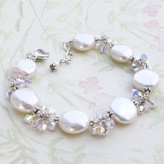 A fun and modern twist to a classic pearl bracelet handmade with freshwater coin pearls, accented with bright and opalescent Swarovski crystals, and set in sterling silver or gold filled. Gorgeous quality and perfectly polished white coin pearls makes for a lovely keepsake gift for brides, their mothers and for women born in June. Pearl is the birthstone for June born women. Bracelet Details: - Bracelet length is 7 to 8 inches long - Freshwater coin pearls are 14 mm in diameter - Pearl bracelet Adjustable Mother Of Pearl Bracelets For Weddings, Adjustable Mother Of Pearl Wedding Bracelets, Elegant Mother Of Pearl Wedding Bracelet, White Mother Of Pearl Bracelets For Wedding, White Mother Of Pearl Bracelet For Wedding, Wedding Jewelry With Round Mother Of Pearl Beads, Wedding Jewelry With Beaded Mother Of Pearl, White Jewelry For Mother Of The Bride, Coin Pearl Earrings