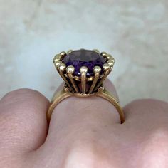 A bold vintage ring featuring an oval-cut amethyst center stone that weighs approximately 7 carats. This ring is mounted in 14k yellow gold. The center is surrounded by a halo of gold bead-shaped prongs. This ring was made in the 1970’s.
The measurements of this ring are approximately 17.82mm x 15.27mm.
The current size of this ring is 4.75 and can be resized at no extra cost.
Ready to Make It Yours? Contact us to reserve this ring and to get more info! Timeless Oval Gold Amethyst Ring, Timeless Gold Oval Amethyst Ring, Timeless Yellow Gold Amethyst Ring With Oval Shape, Classic Gold Amethyst Solitaire Ring, Gold Solitaire Amethyst Ring For Formal Occasions, Timeless Yellow Gold Amethyst Ring, Classic Oval Amethyst Ring With Prong Setting, Classic Yellow Gold Amethyst Ring, Vintage Oval Solitaire Amethyst Ring