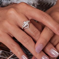 a woman's hand with a diamond ring on her finger and the other hand holding an engagement ring