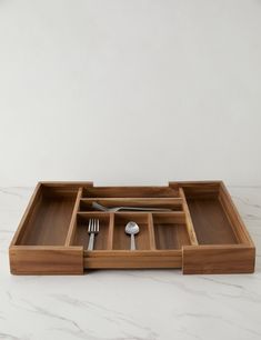 a wooden tray with utensils and spoons in it on a marble surface