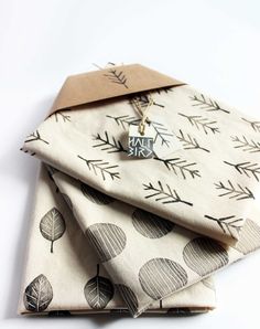 three folded napkins with trees on them, one has a tag attached to it