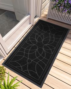 a black door mat sitting on top of a wooden floor next to a potted plant