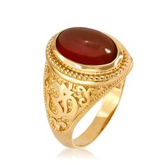 a gold ring with a red stone in the center and an intricate design on it