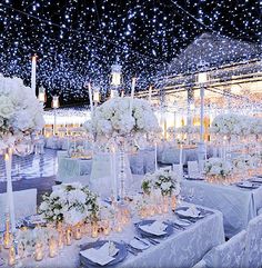 the tables are set with white flowers, candles and centerpieces for an elegant wedding