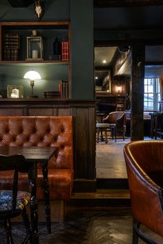 the interior of a bar with leather chairs and tables