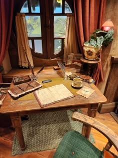 an old desk and chair in front of a window with red drapes on the windowsill