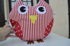 an owl stuffed animal sitting on top of a table next to a person's hand