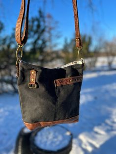 "A stylish midsize bag that combines functional design with fashion for everyday use!  I added details like leather trim on the exterior pocket, brass snaps for texture and rectangle hardware to give the bag depth and design on the black waxed canvas. This bag is based on a bucket bag but is a mishmash of several patterns and my own details to come up with this style that I love.  The front exterior is black waxed canvas combined with a base of supple rich brown leather.  The rich brown leather On-the-go Satchel Shoulder Bag With Brass Hardware, Waxed Canvas Bags With Leather Trim For On-the-go, On-the-go Waxed Finish Shoulder Satchel, Vintage Satchel Shoulder Bag With Gunmetal Hardware, Vintage Black Bags With Leather Trim, Vintage Shoulder Bag With Gunmetal Hardware For Daily Use, Everyday Tote Shoulder Bag With Brass Hardware, Coated Canvas Tote Shoulder Bag With Waxed Finish, Coated Canvas Shoulder Bag With Brass Hardware