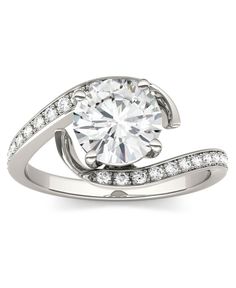 a white gold engagement ring with diamonds on the band and a round cut diamond in the center