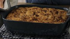 a large casserole dish is sitting on a table with a woman's legs in the background