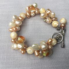 "Cream colored mixed drop pearls. Lampwork glass drops clustered braclet. 8mm faceted cream mother-of-pearl round beads. Tiny seed pearls.  7 and 1/2 \" long. Can be extended 1/2 \" upon request to seller by message seller. Sterling silver Toggle and findings." Handmade Cream Pearl Bracelet With Round Beads, Adjustable Cream Pearl Bracelet, Handmade Cream Pearl Beaded Bracelets, Adjustable Cream Pearl Beaded Bracelet, Adjustable Cream Pearl Beaded Bracelets, Elegant Adjustable Apricot Jewelry, Cream-colored Round Pearl Bracelet, Cream Pearl Beaded Bracelets With Round Beads, Cream Pearl Beaded Bracelet With Round Beads