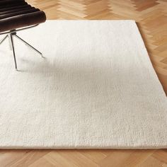 a chair sitting on top of a wooden floor next to a white rug with a black chair