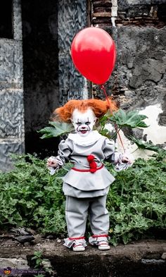 a creepy clown is holding a red balloon