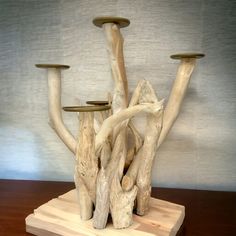 a sculpture made out of driftwood with three candles on each side and one candle holder in the middle