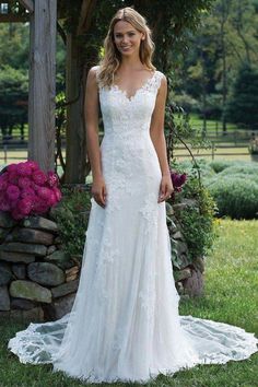 a woman standing in front of a stone wall wearing a wedding dress