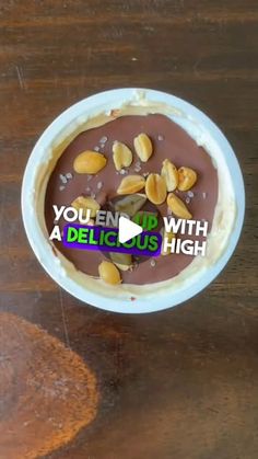 a bowl filled with pudding and nuts on top of a wooden table next to a piece of bread