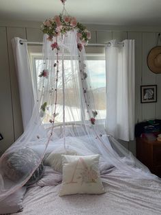 a canopy bed with flowers on it in front of a window and some white curtains