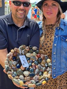 a man and woman standing next to each other holding a plate with rocks in it