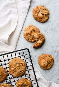 chocolate chip cookies cooling on a wire rack next to a white towel and two glasses of milk