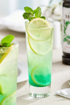 a green drink with lime and mint on the side