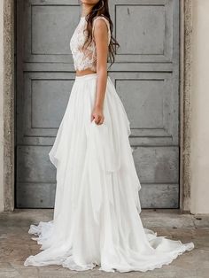 a woman standing in front of a gray door wearing a white dress and headpiece