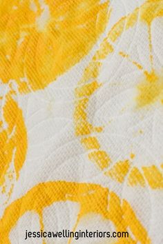 the yellow and white fabric has been painted with oranges, lemons, and leaves