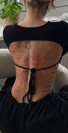 a woman sitting on top of a chair with tattoos on her back