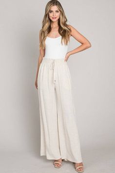 Embrace comfort and style with our Soft Linen Smocked Waist Wide Leg Pants, perfect for your resort collection. Designed with an elastic waistband, these pants ensure all-day comfort and a flexible fit. The wide-leg design adds a touch of elegance and creates a flowing silhouette, ideal for any casual or upscale event. Available in versatile Black and Natural colors, these trousers are a superb choice for those seeking both style and convenience. Constructed from a blend of 60% cotton and 40% linen, these pants are travel-friendly with easy care instructions and reduced wrinkling. Offered in sizes Small, Medium, and Large, they are designed to cater to a variety of body types, ensuring a great fit for every wearer. Ideal for lounging in luxury or stepping out in style, these wide-leg trous Summer Vacation Wide Leg Pants With Pull-on Style, Casual Summer Pants With Gathered Waist, Stretch Bottoms With Drawstring For Vacation, Relaxed Fit Bottoms With Gathered Waist For Vacation, Summer Wide Leg Stretch Pants With Drawstring, White Bottoms With Gathered Waist For Summer, Summer Pants With Gathered Waist And Loose Hips, Casual Bottoms With Gathered Waist For Day Out, Summer Pants With Gathered Waist And Loosely Fitted Hips