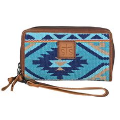 Organize in style with the Mojave Sky Kacy Blue Serape Organizer by STS. Showcasing a trademarked multicolor serape with tan leather accents, this statement-making piece is crafted with full grain leather and features an exterior zip closure, a removable wristlet strap, and interior zip pockets. With 32 card slots, it's the perfect way to organize your essentials, making it both stylish and practical. Multicolor blue serape with tan leather accents Genuine full grain leather Exterior zip closure Western Handbags, Sky Collection, Southwestern Patterns, Desert Sky, Bright Turquoise, Aztec Pattern, Leather Accents, Leather Wristlet, Boots For Sale