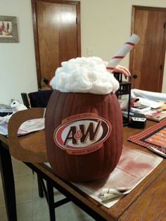 a wooden table topped with a giant pumpkin covered in whipped cream and the word aw on it