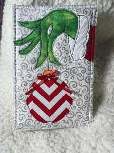 an ornament is hanging on the side of a white blanket with red and green designs