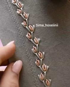 someone is stitching flowers on the side of a piece of fabric with pink thread