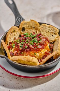 a skillet filled with food on top of a white plate next to some crackers