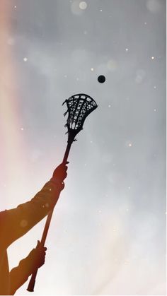 the silhouette of a lacrosse goalie holding a stick with a ball in the background