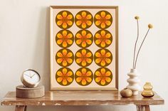 an orange and yellow art piece sitting on top of a wooden table next to a clock