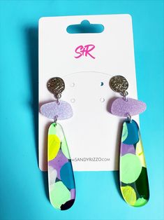 two pairs of colorful earrings on top of a blue background with the word srr written in