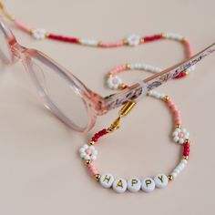 Personalised eyeglass chain. Beaded flower glasses chain.  Fun accessory for any glasses or sunglasses. This fun and cute glasses cord is made using glass seed beads, gold letter beads, gold plated accent beads and adjustable rubbers to use on any glasses ( see photos for details). Can be personalised with any name or wording you like. Chain should not come into contact with water, chemicals or perfume. Please also take off while showering or swimming. Made with love. Flower Glasses, Beaded Glasses Chain, Glasses Cord, Chains Aesthetic, Beaded Glasses, Mama Bracelet, Glasses Chains, Flower Girl Bracelets, Cute Glasses