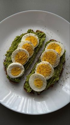 an open face sandwich with eggs on top and avocado in the middle, served on a white plate