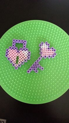 a green plate with two purple and white beads on it's side, next to a black background