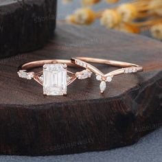 an emerald cut diamond ring on top of a wooden piece