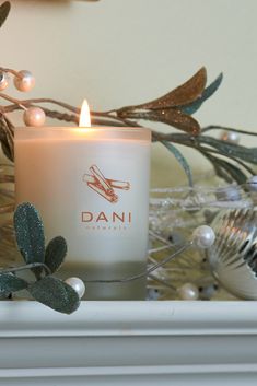 a lit candle sitting on top of a mantle next to a christmas tree and decorations